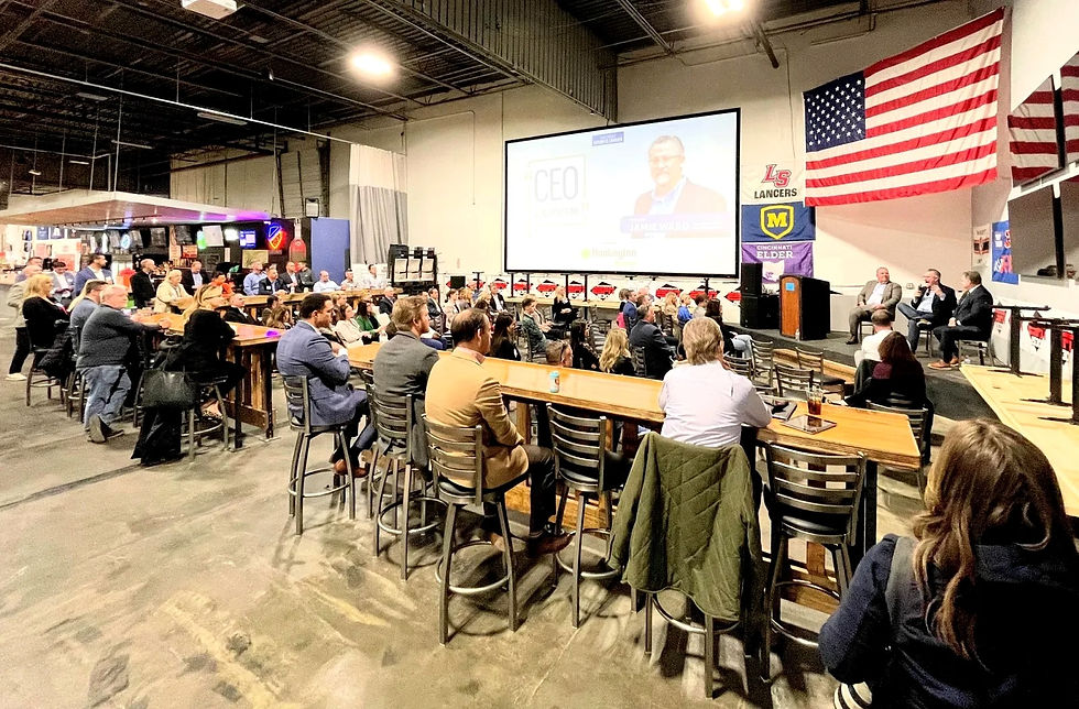 Corporate panel event with a large projection screen and guests at long bar-height tables inside Fowling Warehouse Cincinnati