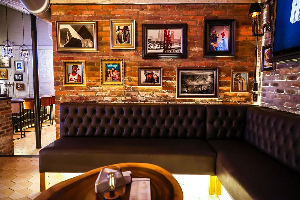 Leather booth seating beneath framed photos on a brick wall at The Grotto in Cleveland