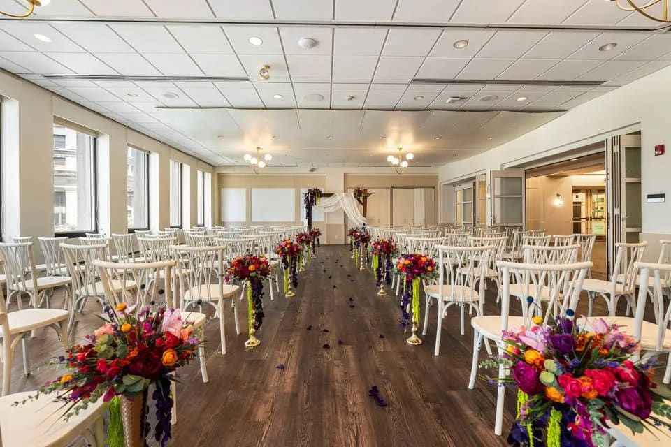 Bright event hall with tall windows and rows of white chairs at Tiffany Glass Space in Cleveland