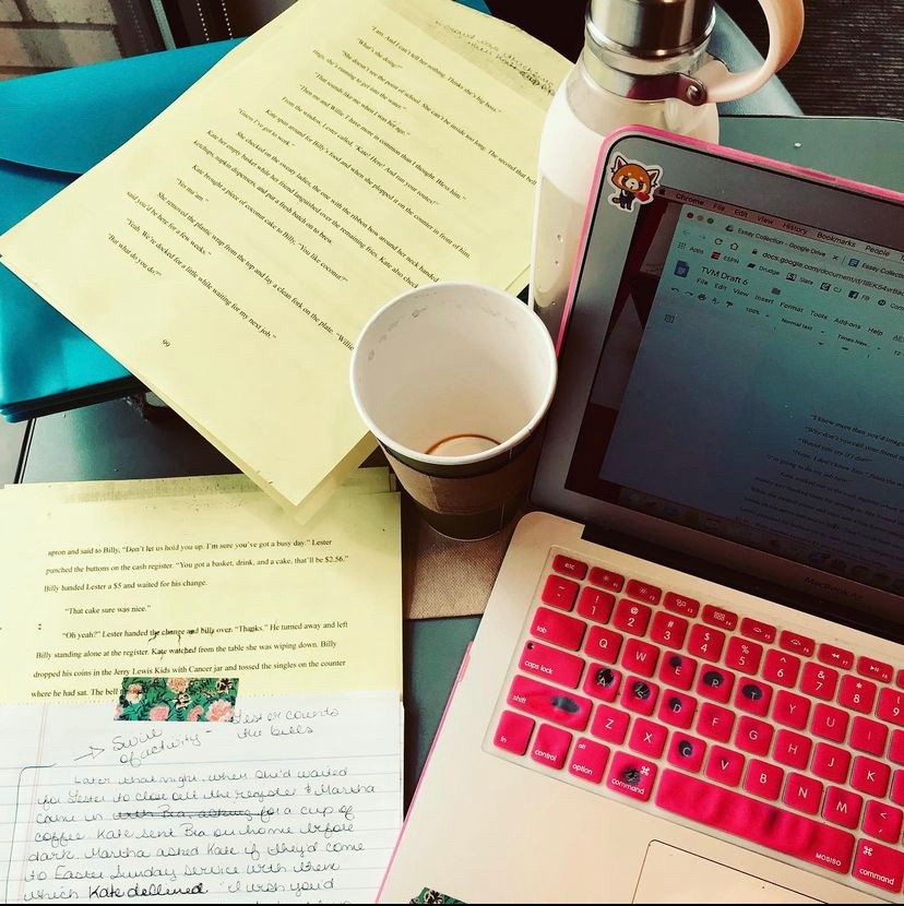Laptop with edited manuscript and empty paper coffee cup