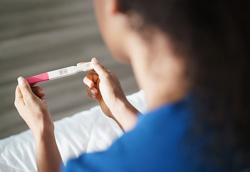 woman looking at a positive pregnancy test