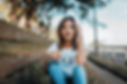 Woman sitting on the sidewalk looking at a camera