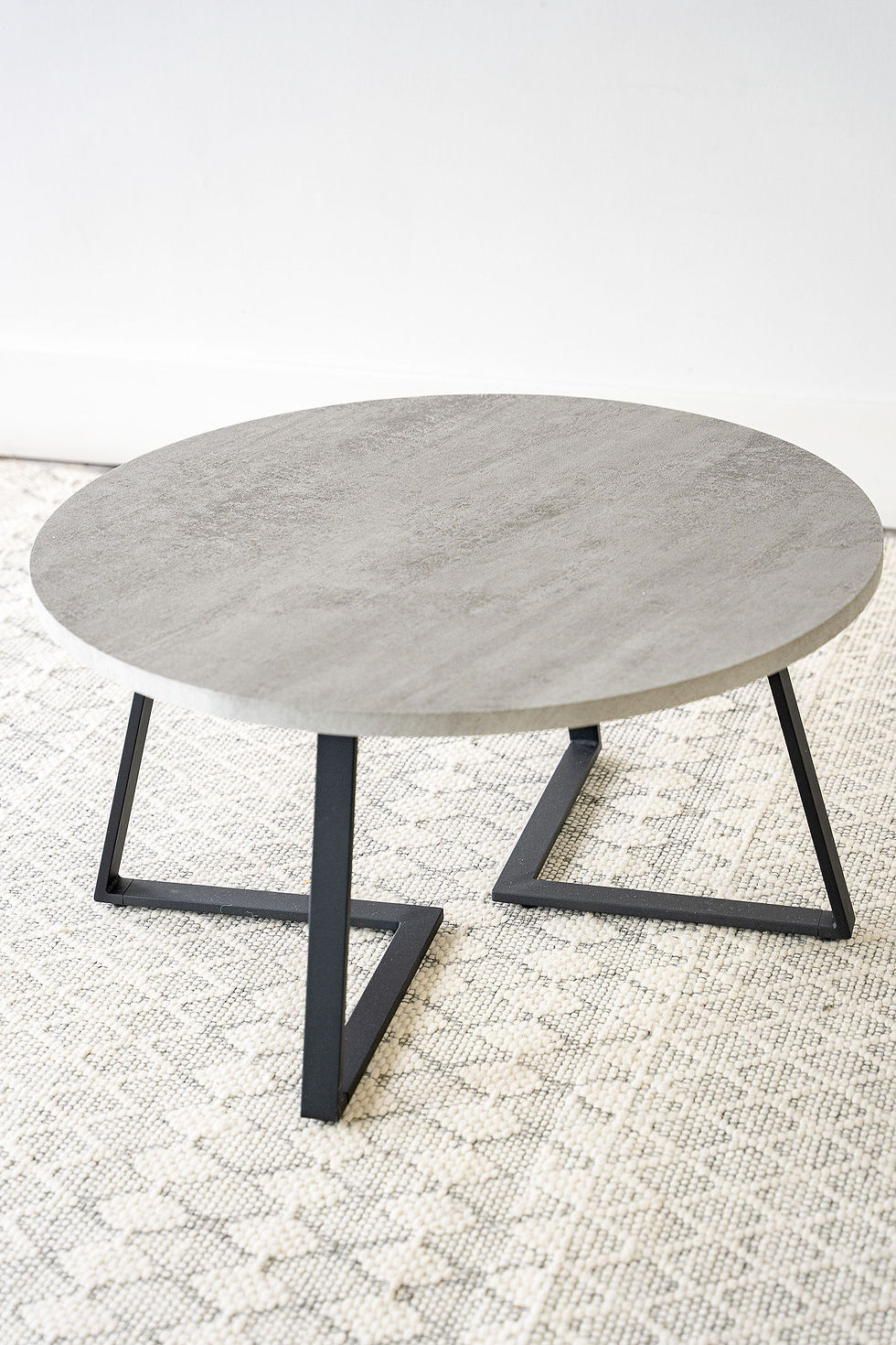 Concrete top black v-shape metal base round coffee table top view