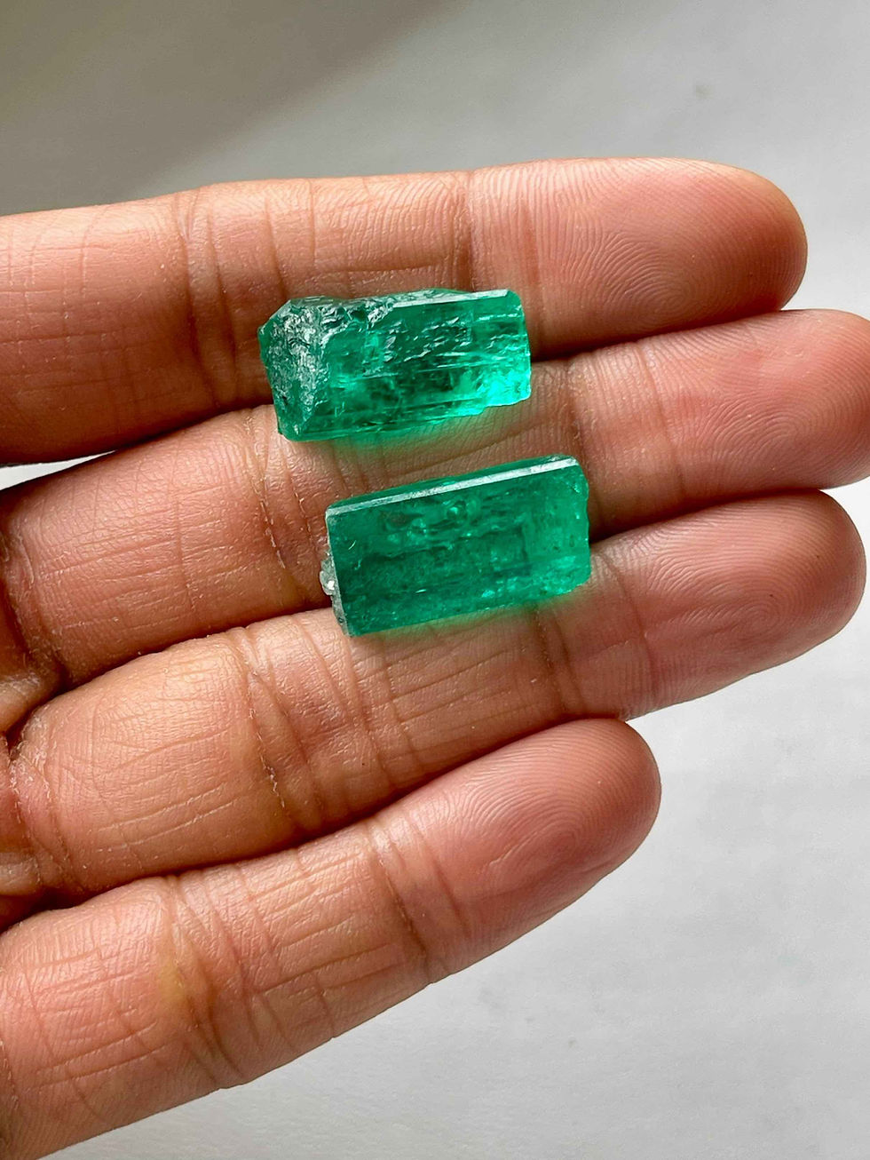 Rahul Jain holding two large pieces of Colombian emerald rough stones