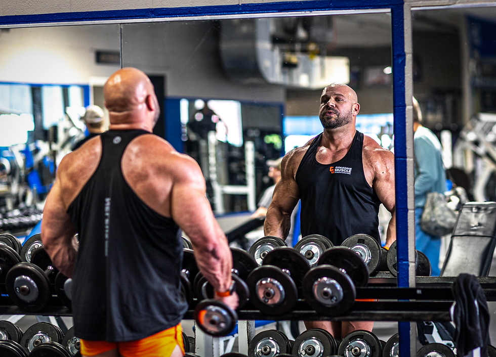 Man training with dumbbells, looking at his reflection in the gym mirror, symbolizing confidence and building the body you want.
