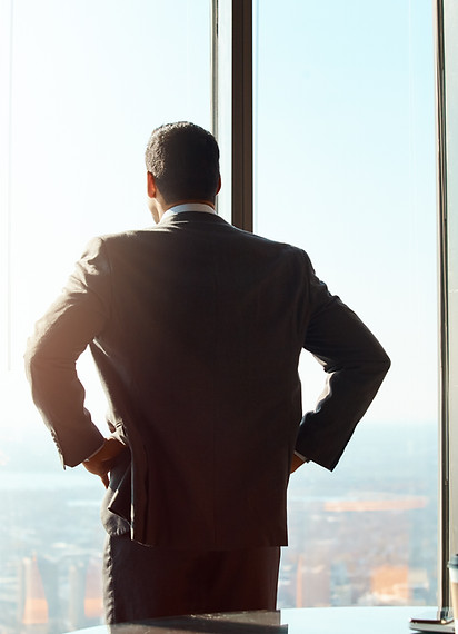 Executive reflecting while overlooking city skyline, symbolizing leadership and growth