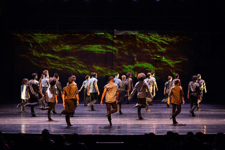 Dançarinos em cena com projeção de paisagem