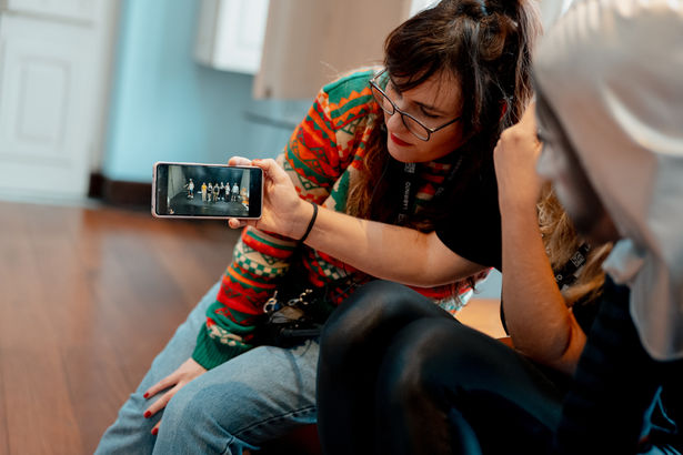 Diretora e coreógrafa assistem juntas a um vídeo em um celular.