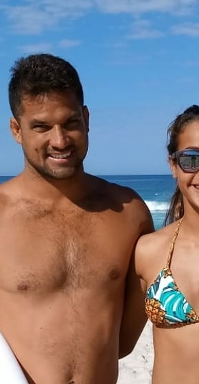 um garoto sem camisa segurando uma prancha branca e uma garota de biquini,apenas a metade da cintura para cima.