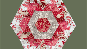 Front view of completed 8 inch English Paper Pieced hexagon rose block, featuring a central hexagon surrounded by half hexagons, diamonds, and triangles in coordinating fabrics.
