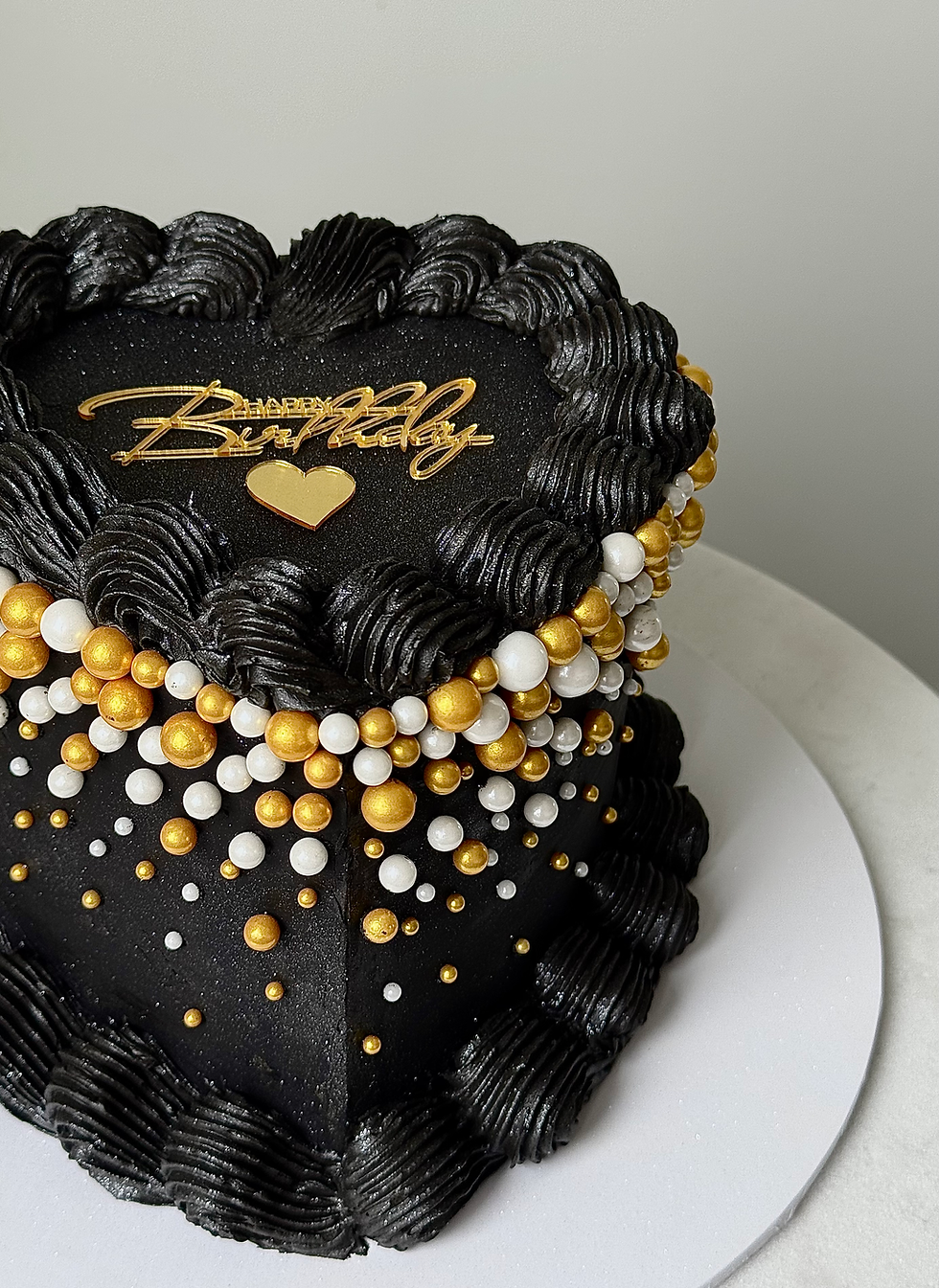 “Luxury black heart-shaped cake decorated with gold and pearl accents”