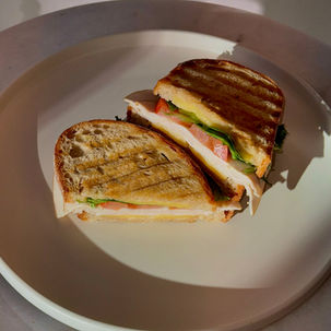 Turkey sandwich on toasted sourdough with lettuce, tomatoes, cheese and Caesar dressing.