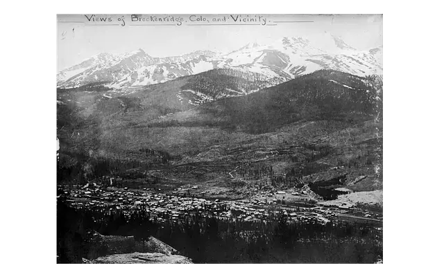 Mountain landscape with snowy peaks, forested hills, and a small town in the valley. Text reads "Views of Breckenridge, Colo., and Vicinity."