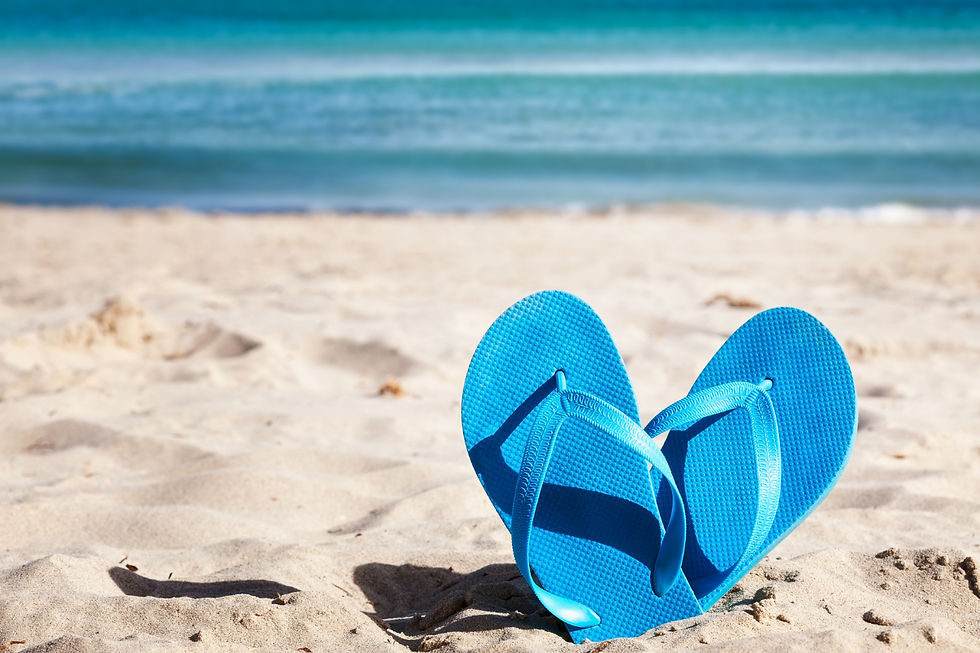 blue ocean, pair of blue flip flops sticking up out of white sand