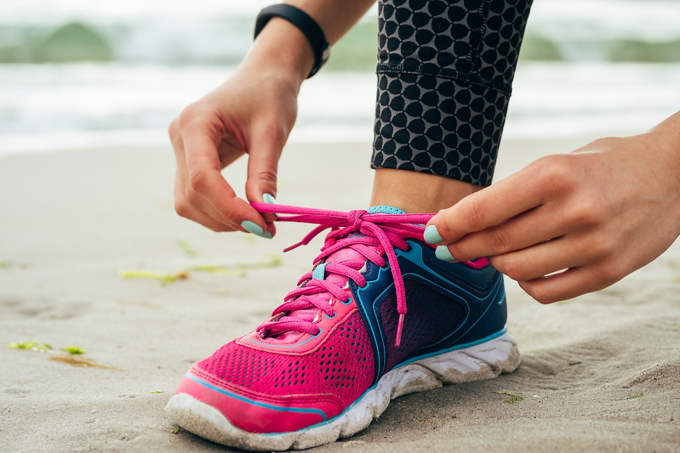 woman's hands with blue nail polish tying pink shoelaces of a blue, pink and white sneaker
