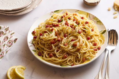 Bowl of carbonara pasta with noodles and crispy pancetta, served with fresh lemon on the side.