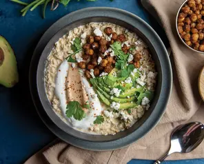 Savory oatmeal topped with crispy roasted chickpeas, sliced avocado, greek yogurt and Once Again® cashew butter.