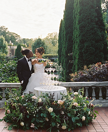 Couple standing in front of a champagne tower adorned with modern floral arrangements repurposed from the wedding ceremony