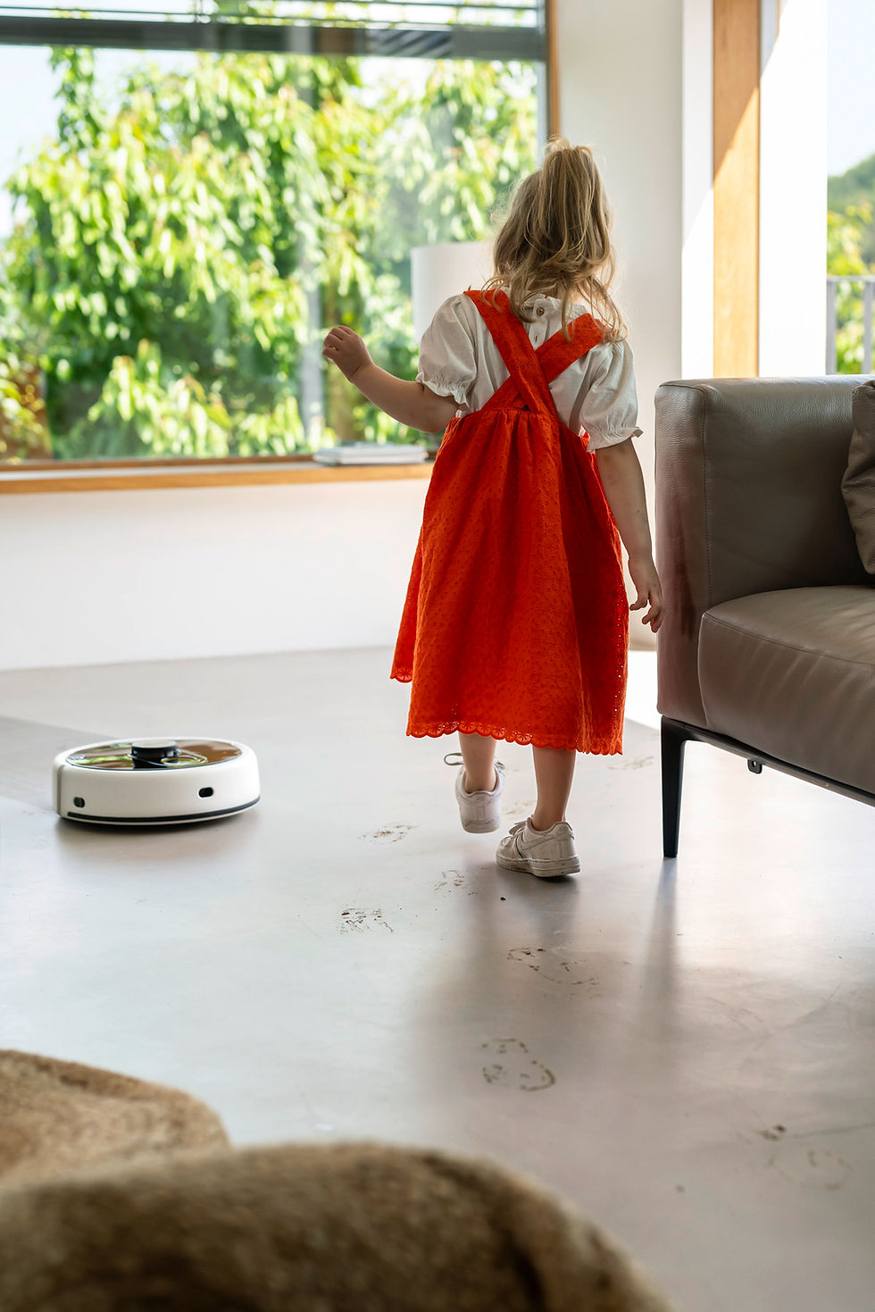Thumbnail: Young girl walks as a robot vacuum cleans the floor in the room.