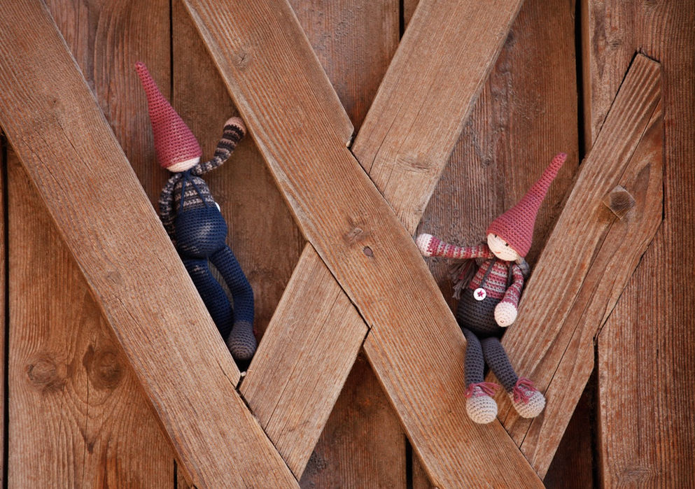 Zwei kleine Wichtel mit roten Mützen klettern auf einer Holztür.