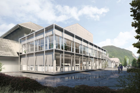 Außenperspektive des neuen Labor- und Bürogebäudes für Calcit in Stahovica. Die 3D-Visualisierung zeigt den eleganten Glaskubus mit außenliegendem Sonnenschutz im Kontext des historischen Fabrikgeländes. Stimmungsvolle Darstellung mit nassem Asphalt und Gebirgslandschaft im Hintergrund.