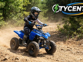 Young rider safely operating a Tycentre kids electric mini ATV featuring full suspension and reverse gear controls on a dirt trail.