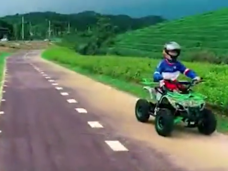A kid rider wearing a safety helmet and gear on a small red 110cc gas ATV in a grassy backyard, showcasing affordable kids' off-road fun.