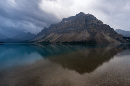 Mountain view reflecting in lake, dark clouds, calm water, Banff National Park, devinshots.
