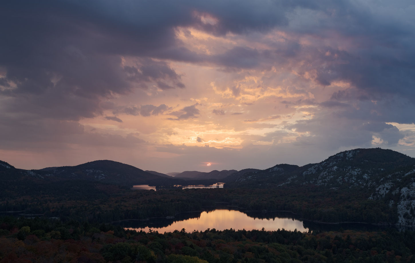 Dramatic sunset over a calm lake, mountains, and colorful clouds; Devin Shaw Photography