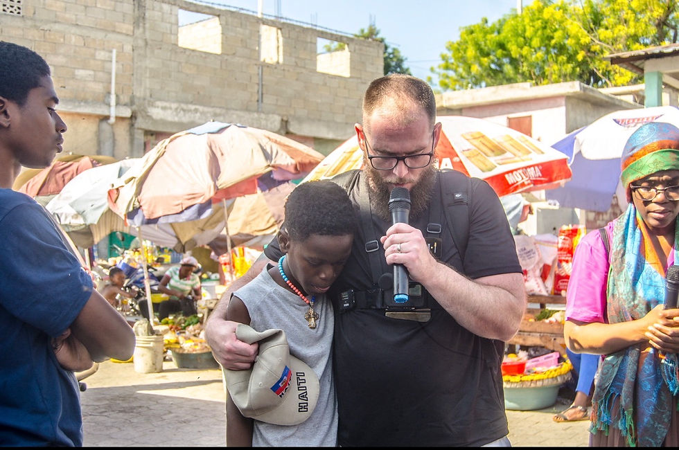 Phillip Blair speaking into a microphone with a resident during a market outreach in Port-au-Prince, Haiti.