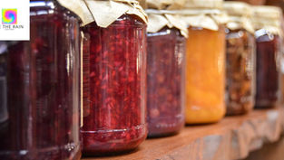 Rows of homemade jam jars on a wooden shelf, with the "Be The Rain Coaching" logo in the top corner. The image illustrates the concept of deferred gratification and the "jam later" promise.
