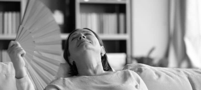 Woman feeling warm and uncomfortable, fanning herself for relief
