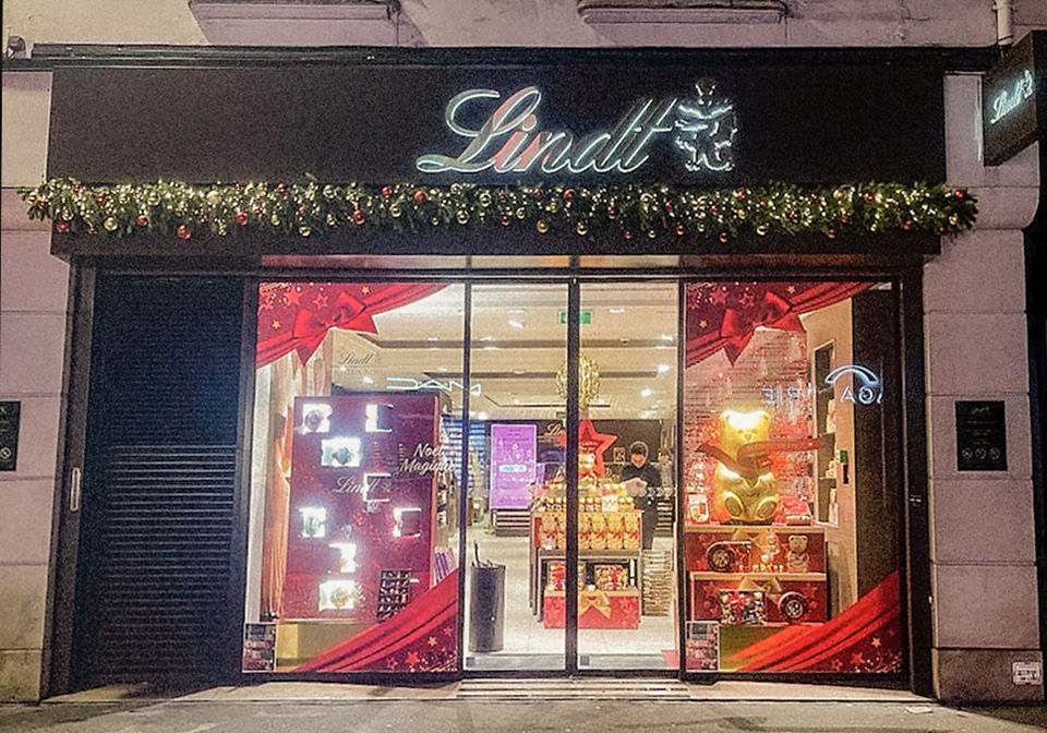 Décoration de Noël pour la boutique Lindt à Paris 16e avec guirlande végétale et boules rouges et dorées