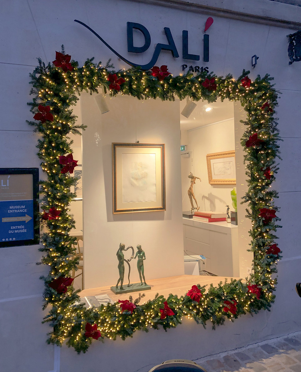 Décoration de Noël pour le musée Dalà à Paris 18e avec arche lumineuse en sapin naturel et fleurs rouges