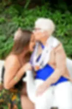 Un doux moment partagé : une femme agée embrasse une jeune femme sur le front, illustrant l'amour et la connexion entre générations.