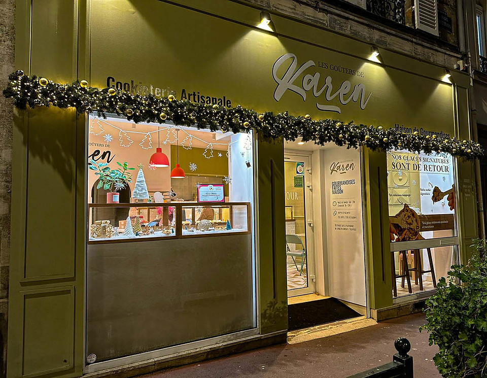 Décoration de Noël en sapin naturel à Asnières avec guirlande végétale lumineuse sur la devanture de la pâtisserie Les Goûters de Karen