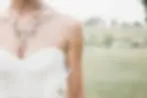 Buste dāune mariĆ©e en robe bustier blanche avec un collier floral dorĆ© et perlĆ©, dans un cadre naturel et champĆŖtre.
