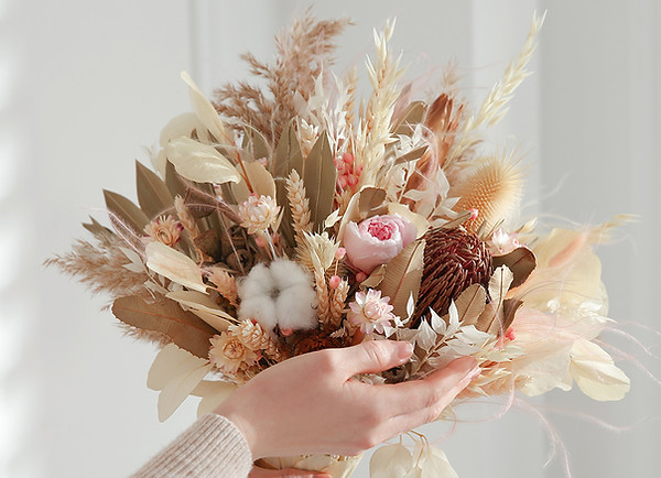 Une main gracieuse portant un bouquet de fleurs séchées, capturant l'essence de la nature dans un style sophistiqué.