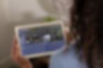 Homeowner using a tablet to control smart home automation including lighting, security, climate, and motorized shades through an integrated control system.