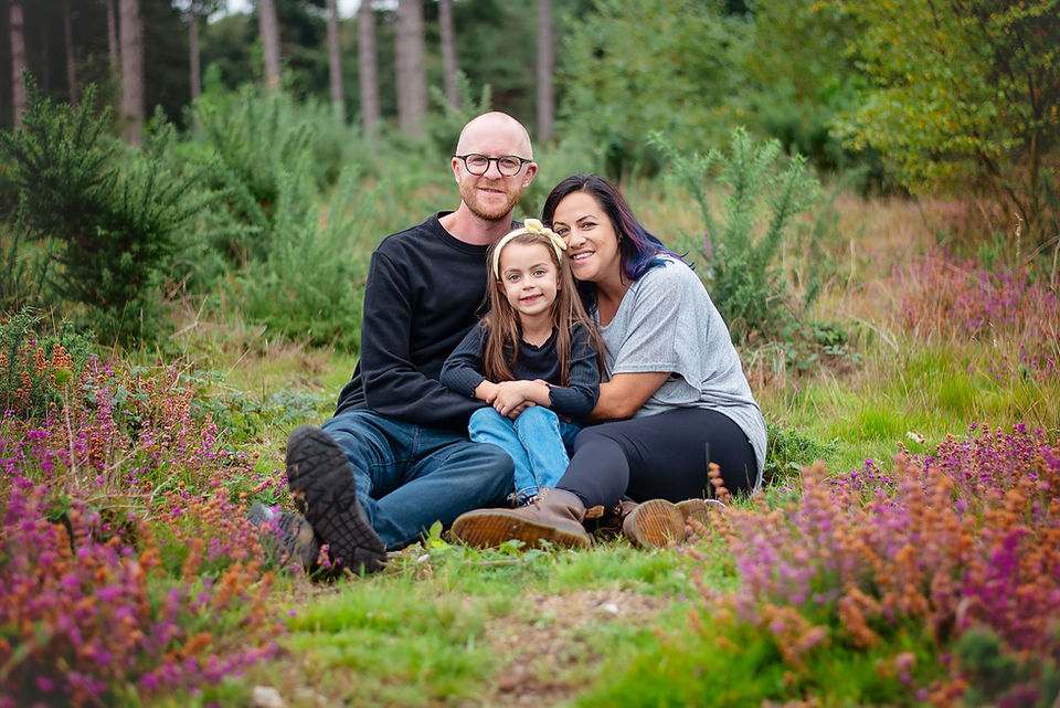 Parents and children cuddling on a forest floor during an outdoor family photoshoot in Suffolk