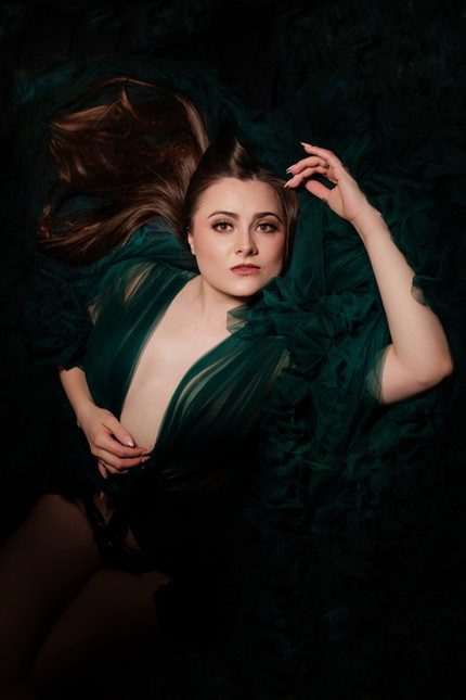 Elegant Bristol boudoir portrait of a woman draped in deep green fabric, photographed with moody studio lighting