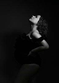 Fine art maternity portrait with dramatic studio lighting and sculptural pose