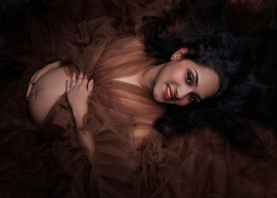 pregnant woman lying in soft tulle fabric artistic maternity photoshoot Bristol