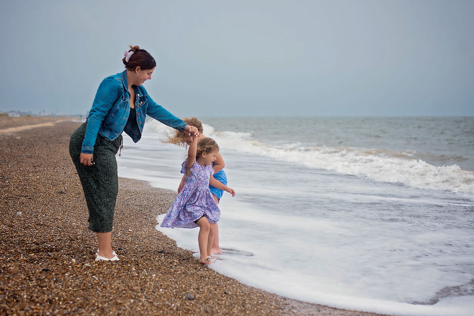 Parent and child playing by the sea during an outdoor family photography session in Suffolk