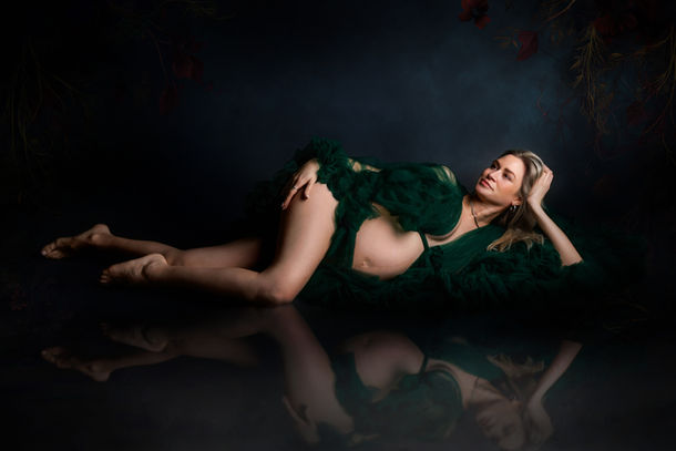 pregnant woman reclining in dark green fabric dramatic maternity photographer Bristol