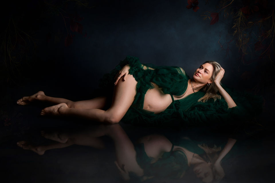 pregnant woman reclining in dark green fabric dramatic maternity photographer Bristol