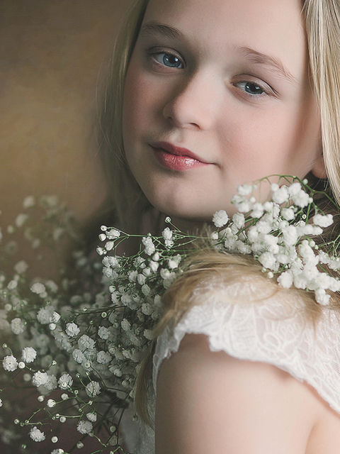 Fine art child portrait with delicate flowers, softly lit studio photography