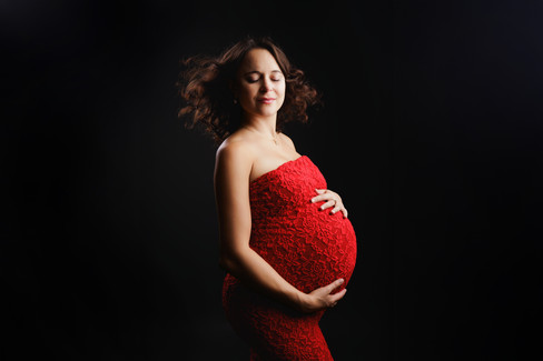 Pregnant woman in fitted red dress during maternity photography session in Bristol