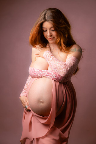 Pregnant woman in soft pink off shoulder knit during light maternity portrait