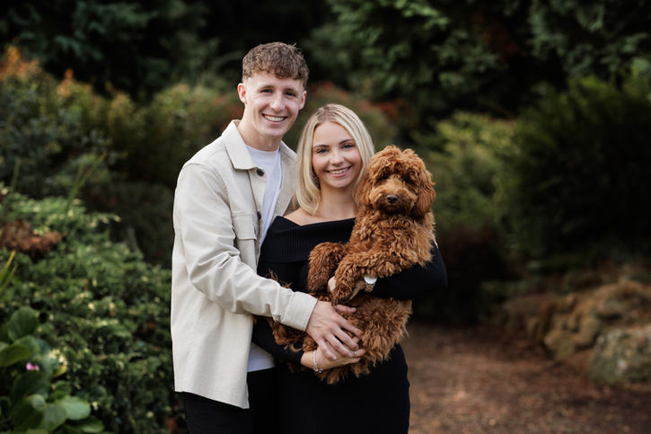 Outdoor family photoshoot in Bristol with a couple holding their dog in a natural setting